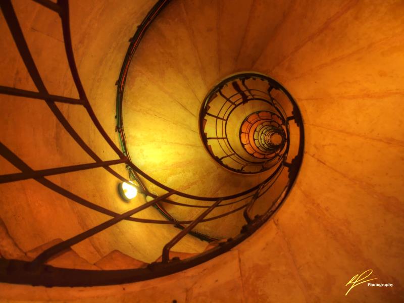 This is an artful shot looking up from inside a stairwell inside the legendary Arc de Triumph in Paris, France.