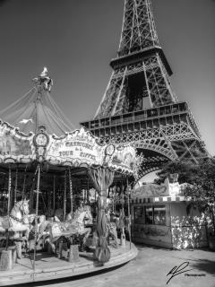 A lovely black and white shot of a merry  round near the base of the famous Eiffel Tower, near the banks of the river Seine in Paris, France. 